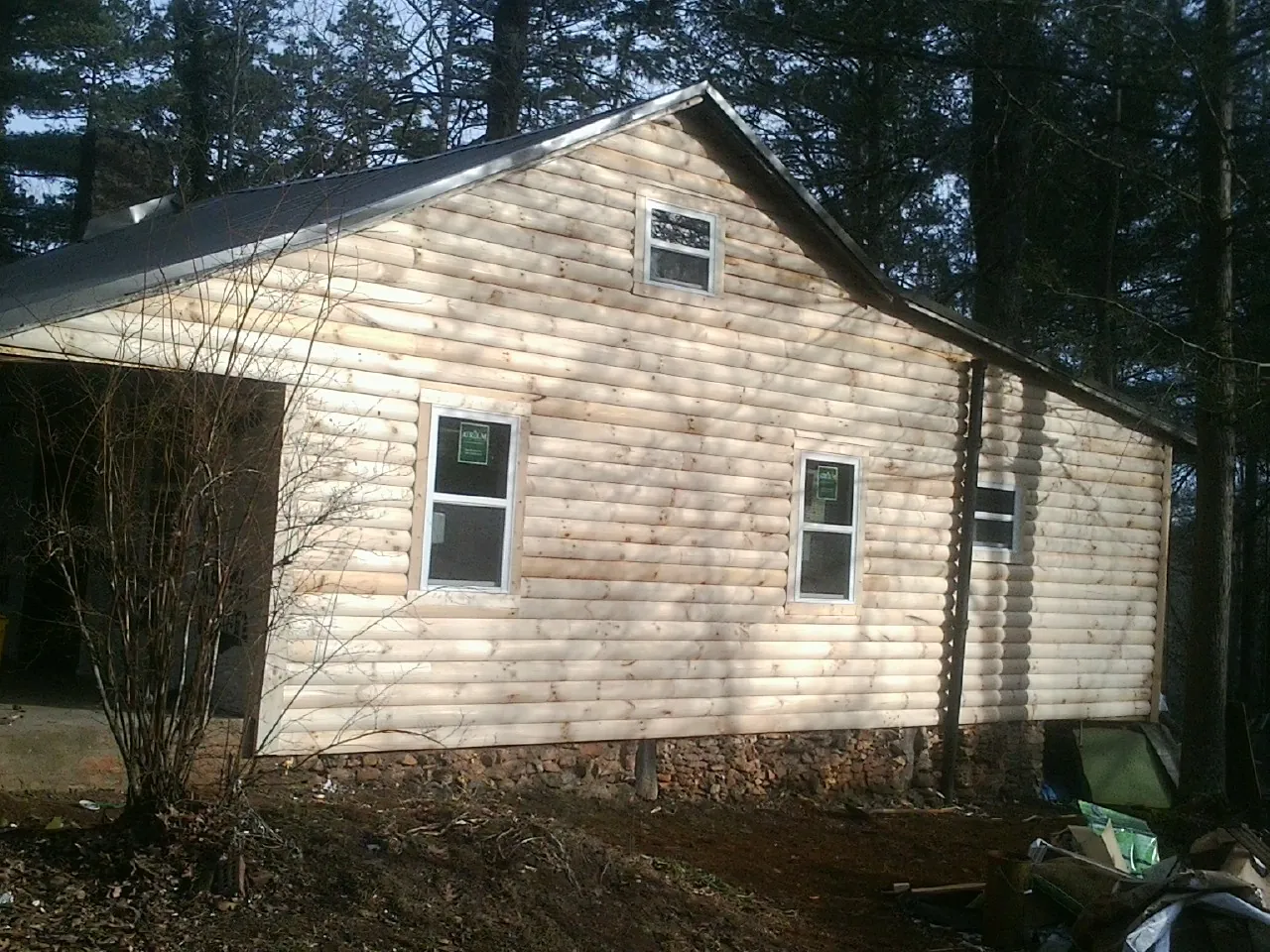 New log siding and dark metal roofing on a gable end in Plymouth
